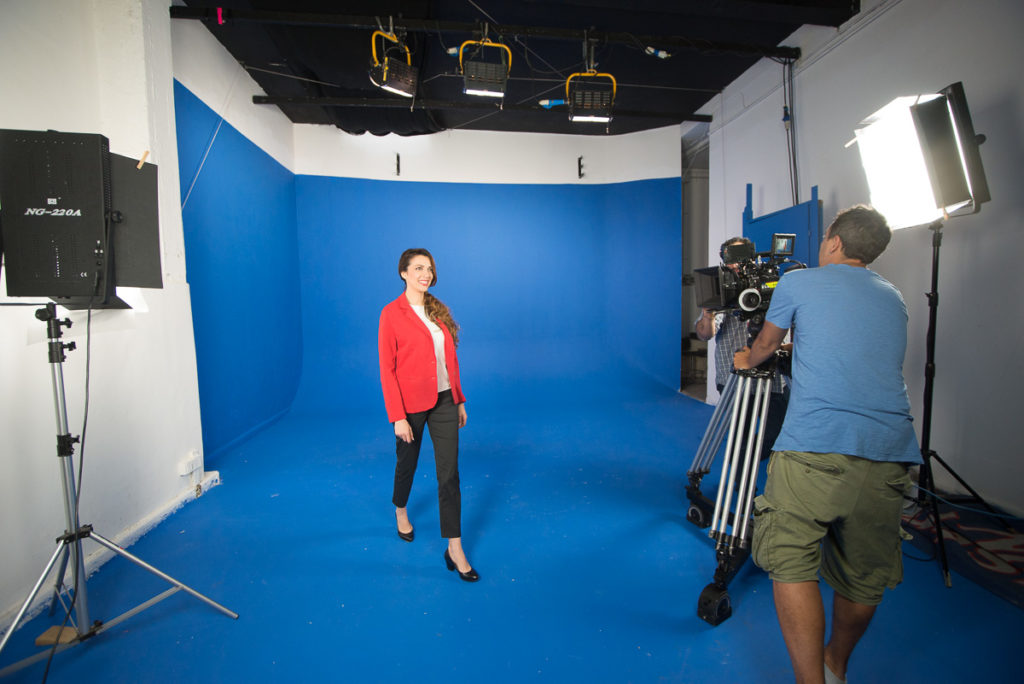 Instudio.org all'interno della sala C una modella con giacca rossa si muove sul Blue Screen