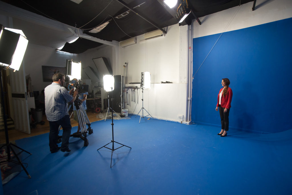 Instudio.org all'interno della sala C una modella con giacca rossa si muove sul Blue Screen